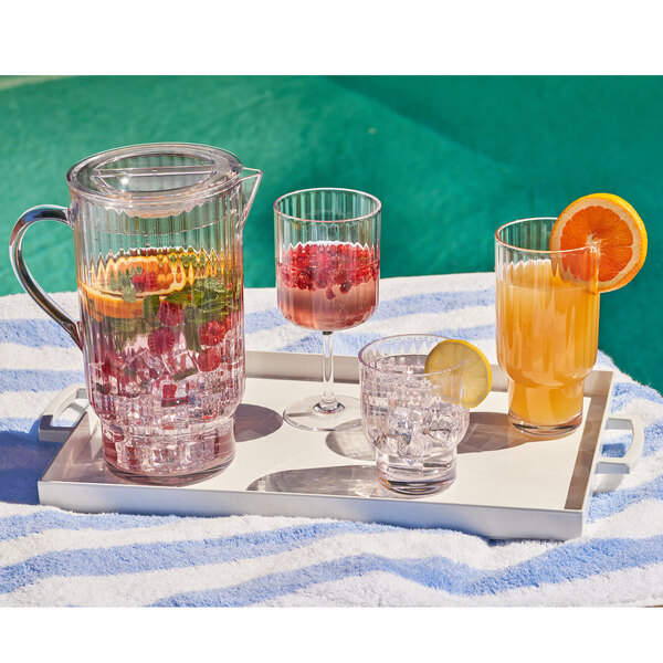 A tray with a pitcher and glasses of fruit juice and a slice of lemon.