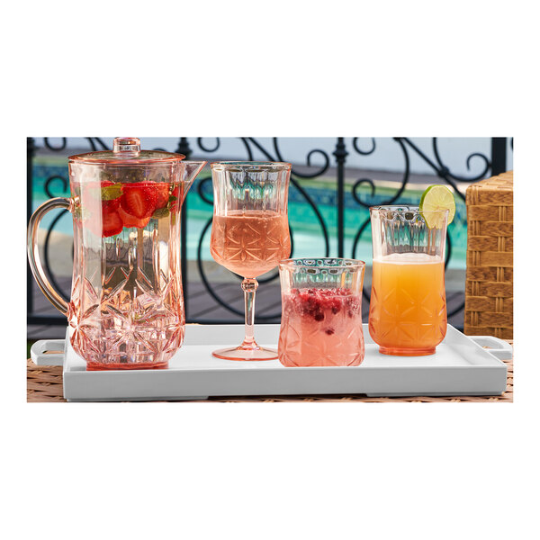 A Sophistiplate blush plastic pitcher with glasses of water and orange juice on a tray.