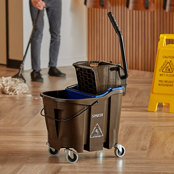 A man using a Carlisle brown mop bucket with a side press wringer.