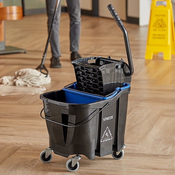 A man using a Carlisle OmniFit mop bucket with side press wringer to clean a floor.