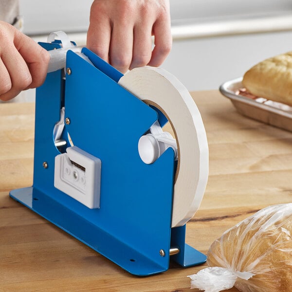 A close-up of a hand putting white plastic tape on a blue tape dispenser.