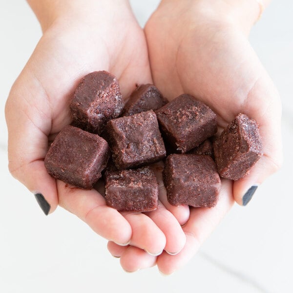 A person holding a pile of Pitaya Foods Acai Berry Bite-Sized Pieces.
