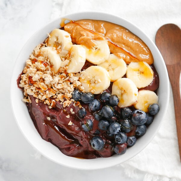 A bowl of Pitaya Foods acai berry pieces with bananas and nuts.