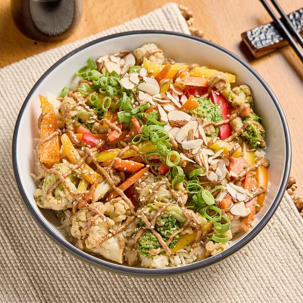 A bowl of rice with vegetables and nuts topped with Bare Nut Butter Salted Almond Butter.