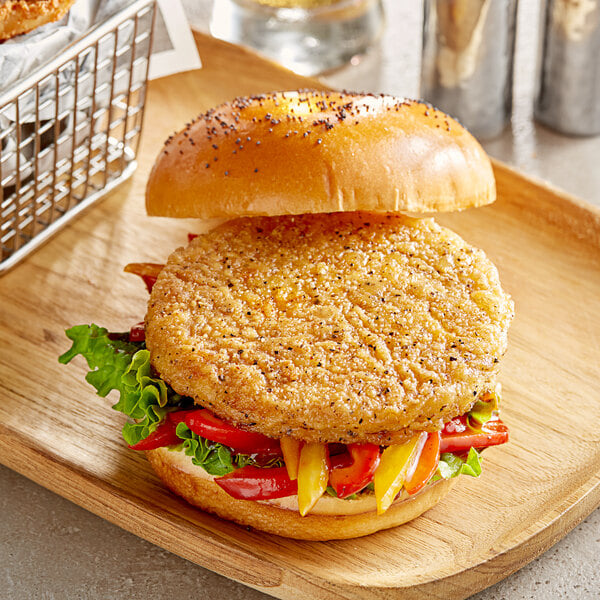 A Daring Foods plant-based chicken patty on a wooden board with a basket of fries.