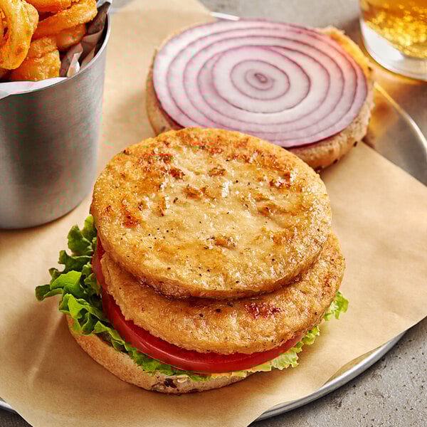 A Daring Foods plant-based chicken patty on a plate with onion rings and fries.