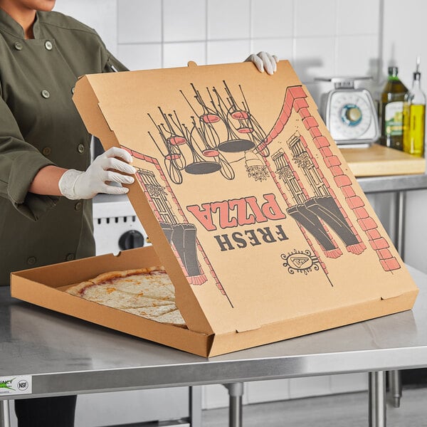 cook putting large pizza in pizza box