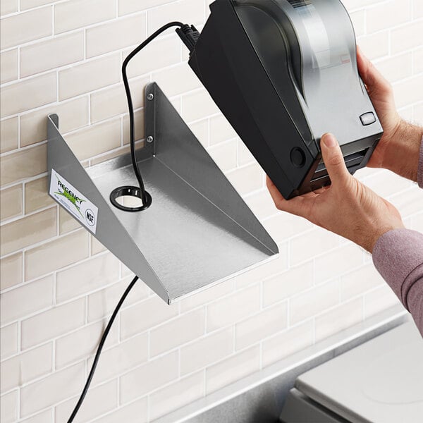 A hand holding a stainless steel wall mounted label printer shelf.