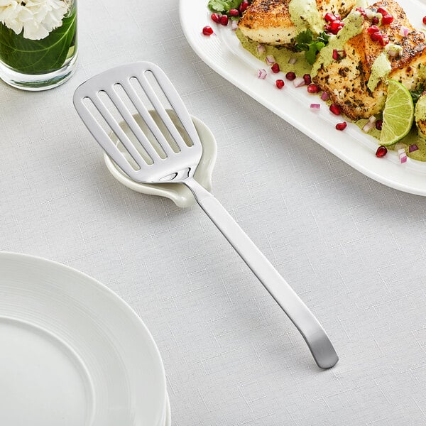 An Acopa stainless steel slotted turner on a plate of food.