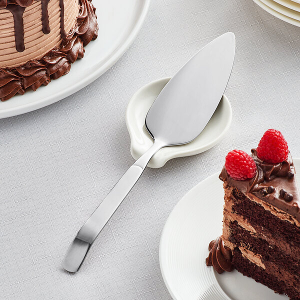 A piece of chocolate cake with raspberries on a plate with an Acopa Skyscraper stainless steel cake server.