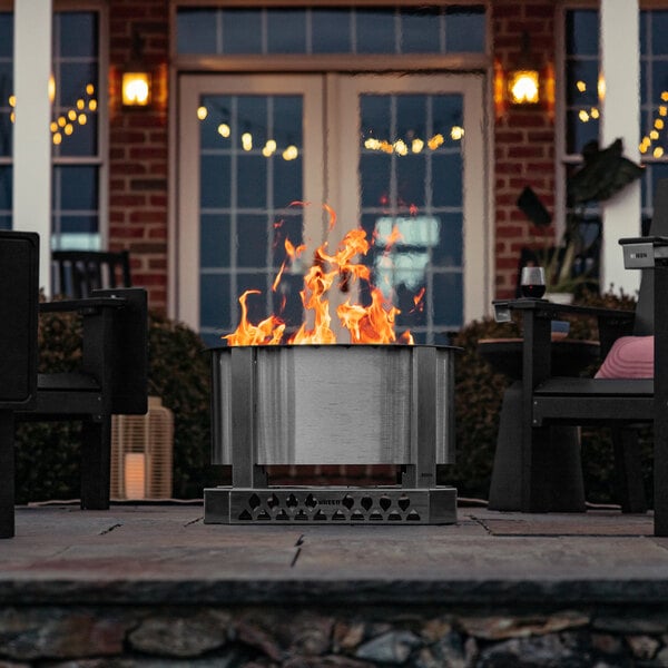 A BREEO stainless steel fire pit on a table on a patio.