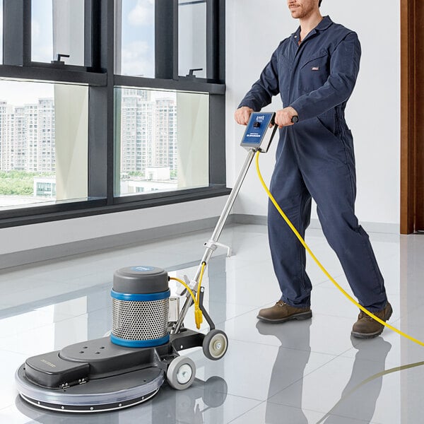 A man in a coverall using a Lavex Pro 20" dust-control burnisher on a floor.