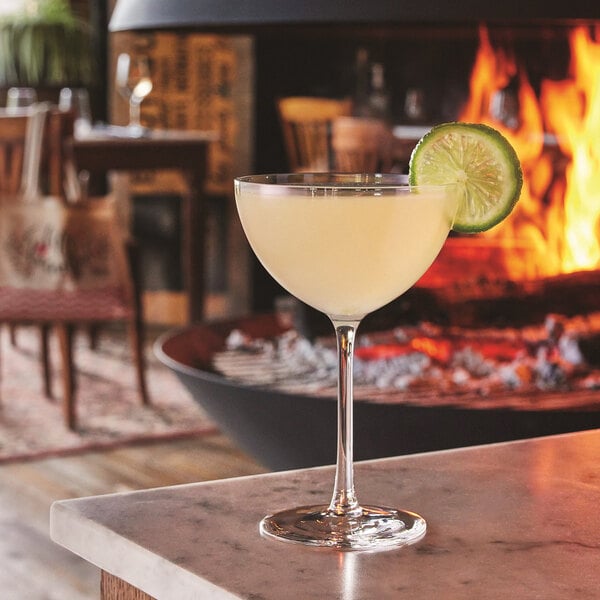 A Chef & Sommelier Sequence coupe glass filled with a white liquid and topped with a lime slice.