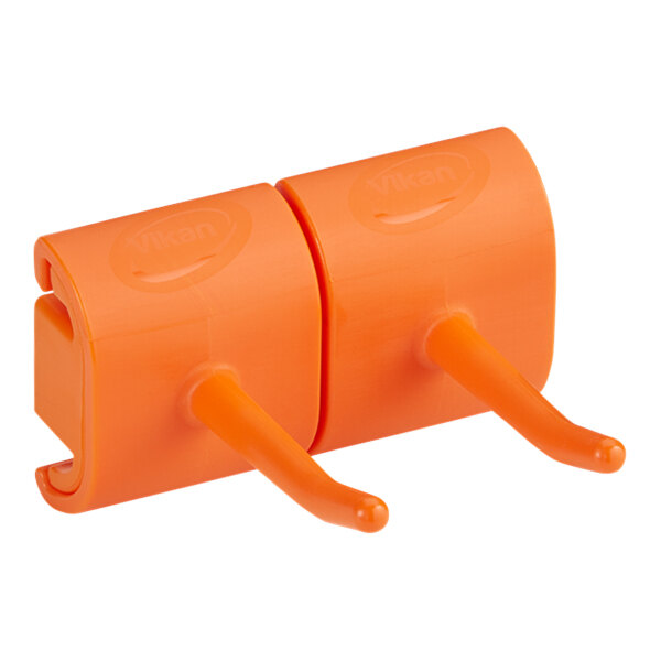 A white Vikan wall bracket with two orange plastic hooks.