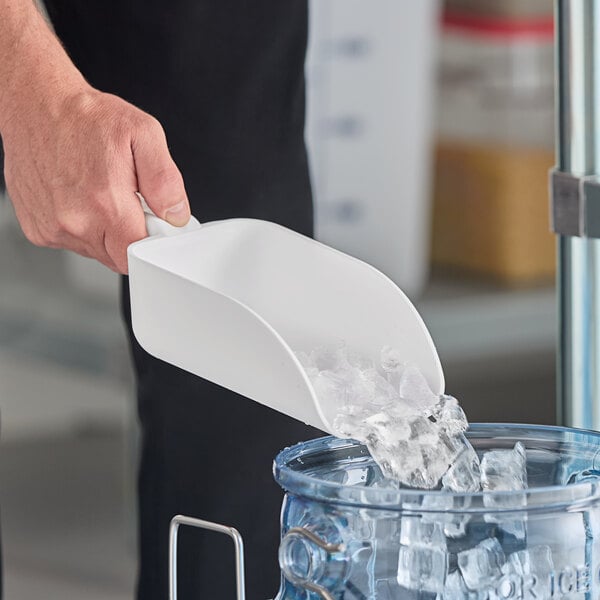 A hand holding a Vikan white polypropylene scoop of ice.