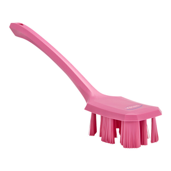 A pink Vikan hand brush with a long handle.