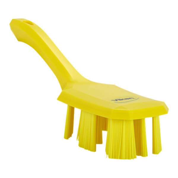 A yellow brush with a short handle and stiff bristles.