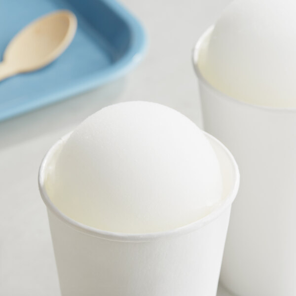 Two white cups of Philadelphia Water Ice Coconut Italian Ice on a white surface.