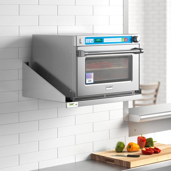 A stainless steel Regency microwave shelf holding a microwave oven on a white wall.