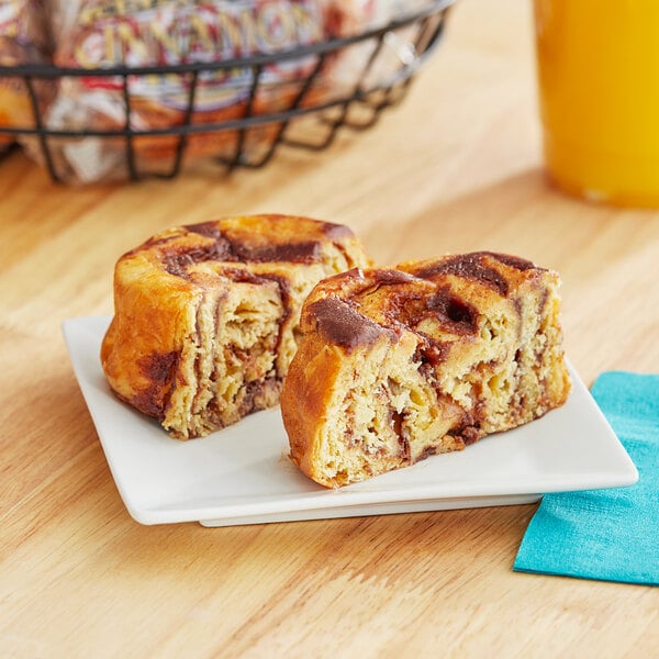 An individually wrapped Ne-Mo's Bakery Old Fashioned Cinnamon Roll on a plate.
