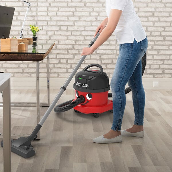 A woman using a NaceCare cordless canister vacuum to clean a room.