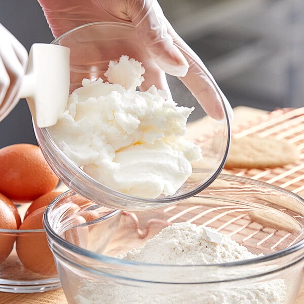 A person pouring Stratas Primex Golden Flex All-Purpose Shortening into a bowl of white powder.