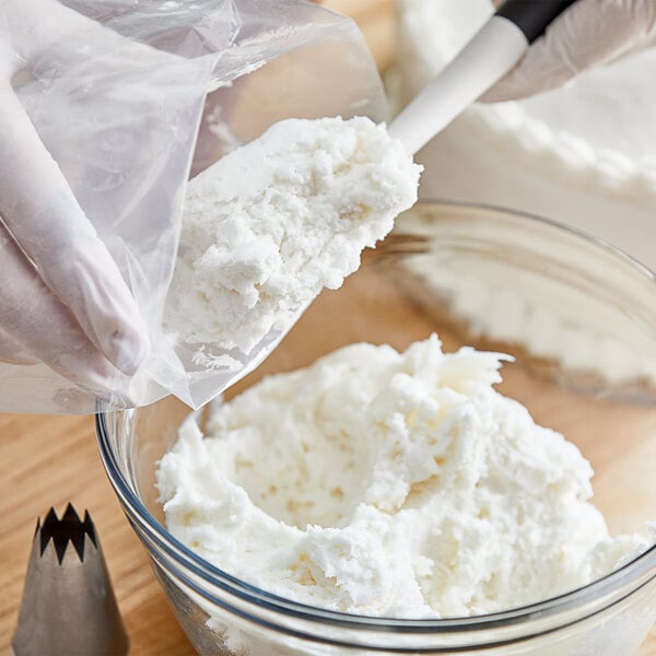 A person mixing Stratas Alpine Soy Flex Icing into a bowl of white cream.