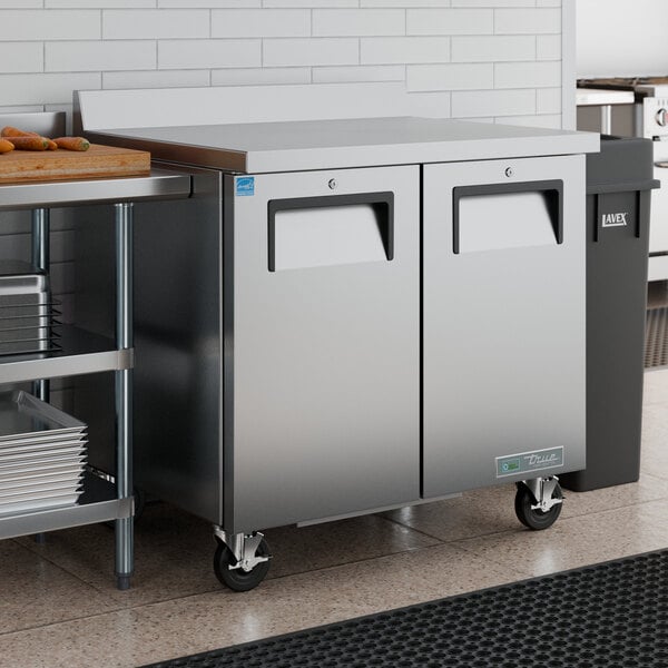 A stainless steel worktop refrigerator with two doors and a backsplash, designed for commercial kitchen use.