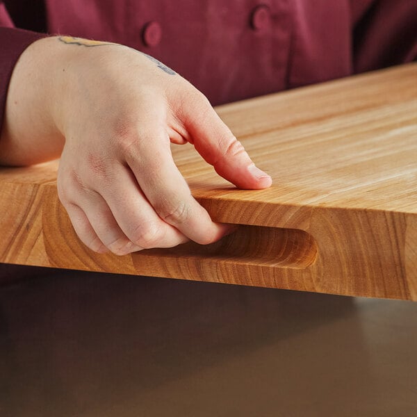 A person holding a Choice wood cutting board with rounded edges.