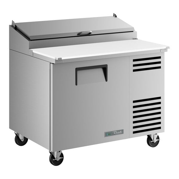 A stainless steel refrigerated pizza prep table with a single door and a raised ingredient rail.