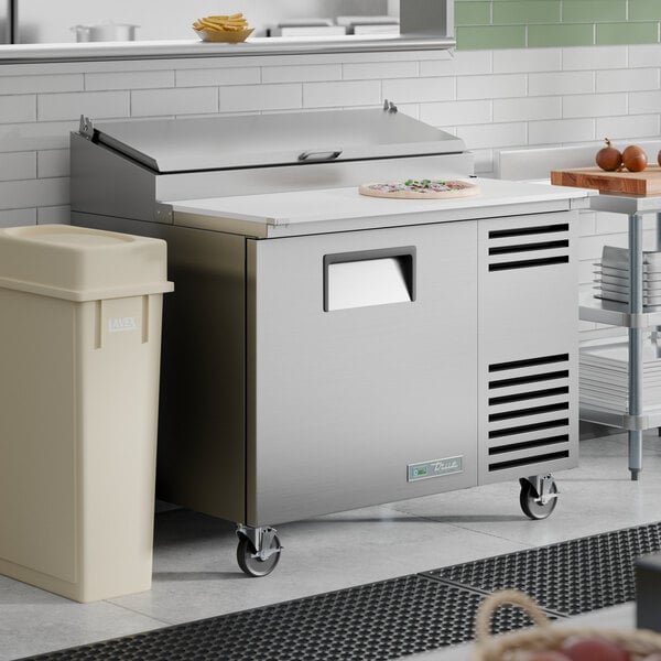 A stainless steel refrigerated pizza prep table with a single door and a white cutting surface on top.