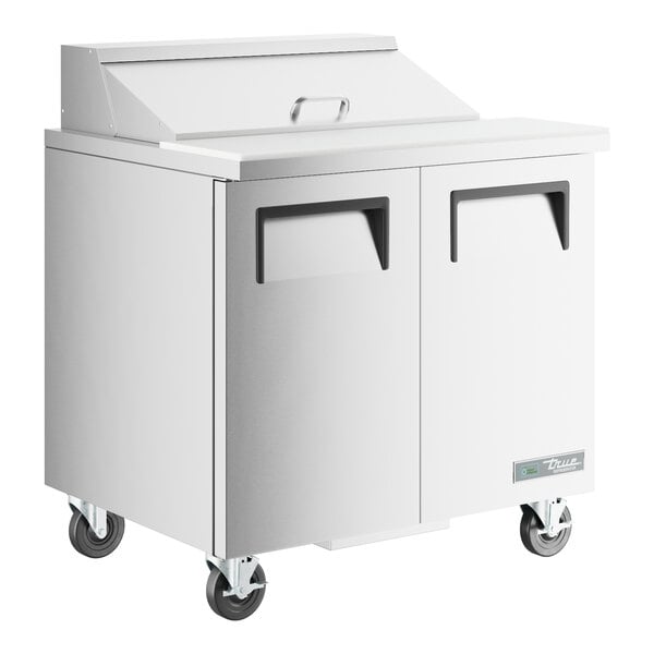 A white True commercial refrigerator with black handles and wheels.