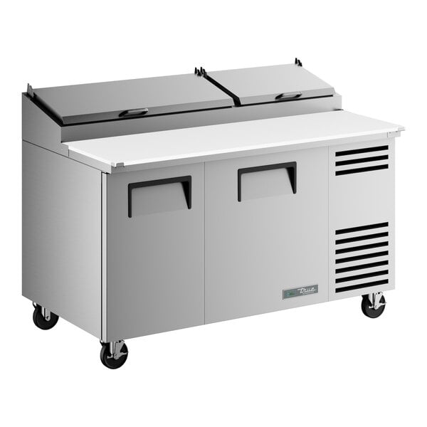 A stainless steel two-door refrigerated pizza prep table with a white cutting surface and dual top lids.