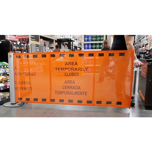 An orange ZonePro safety banner on a metal stanchion.