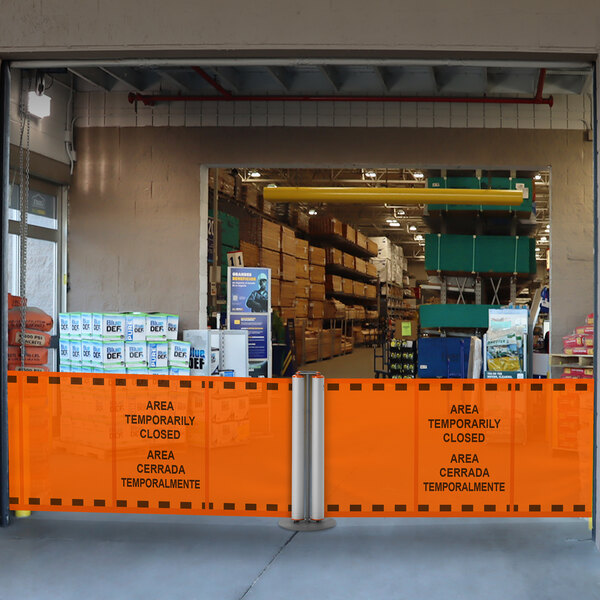 A ZonePro dual rolling stanchion with orange safety banners blocking a store entrance.