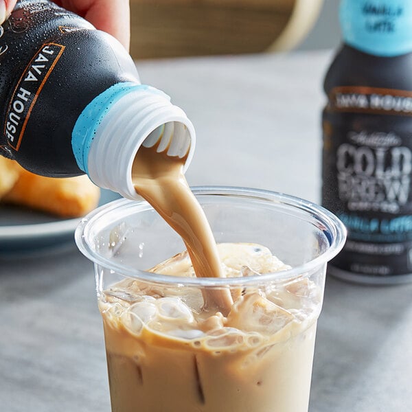 A person pouring Java House Cold Brew Vanilla Latte into a cup.