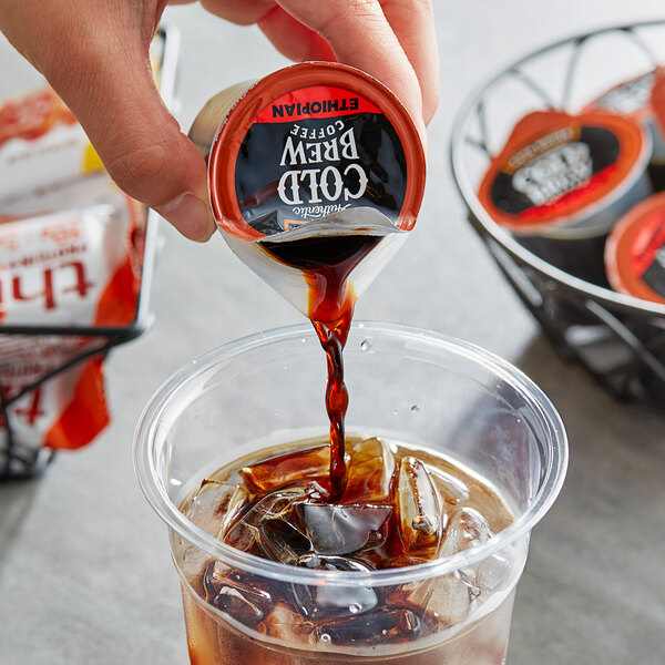 A hand pouring Java House Ethiopian cold brew coffee into a cup.