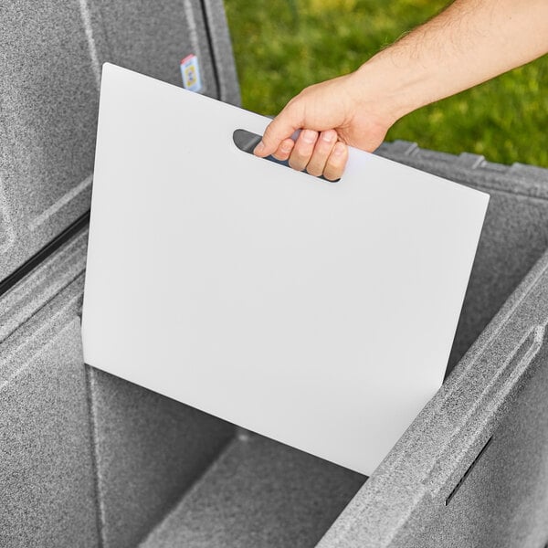 A hand holding a white CaterGator divider for coolers.