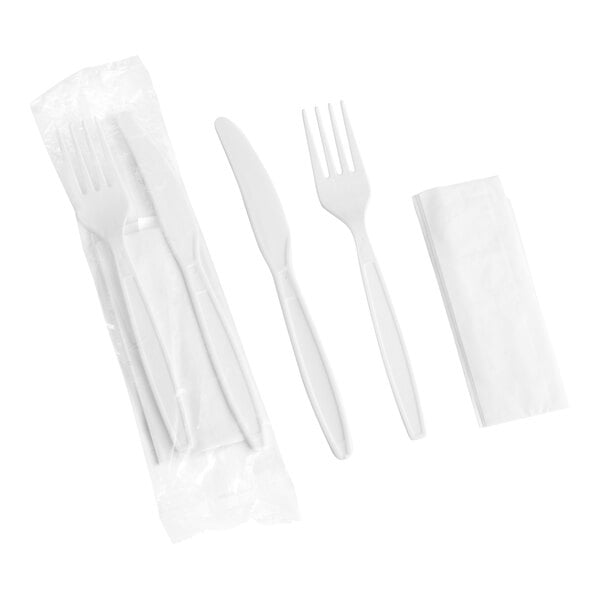 A white heavy weight plastic fork and knife set wrapped in a white napkin.