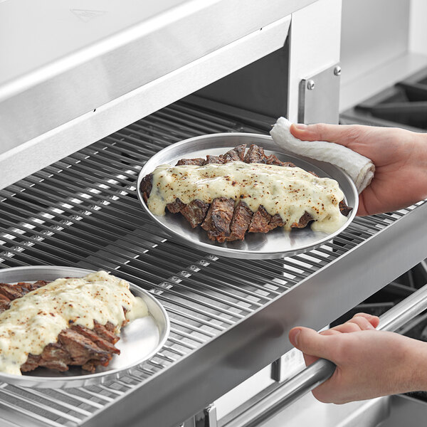 A person holding a Choice round aluminum sizzler platter of food.