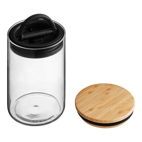 A Planetary Design glass food storage container with a bamboo lid on a wooden surface.