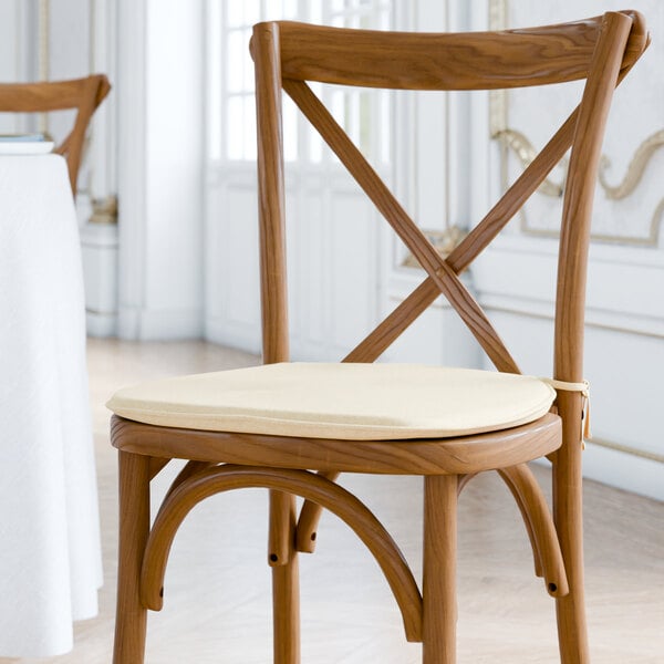 A Lancaster Table & Seating wooden chair with a Chardonnay tan cushion with ties.