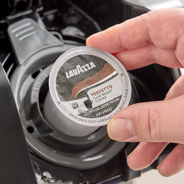 A Lavazza Perfetto dark roast coffee single-serve K-Cup pod being placed into a Keurig coffee machine.