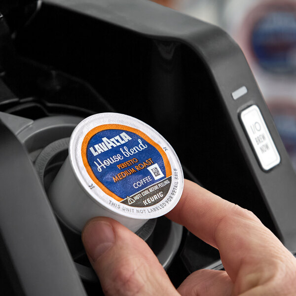 A Lavazza Perfetto House Blend medium roast coffee pod being placed into a Keurig coffee machine.