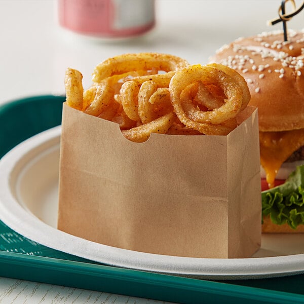 A Bagcraft paper bag of fries next to a burger.