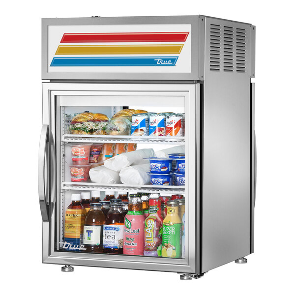 A True countertop glass door refrigerator full of food and drinks.