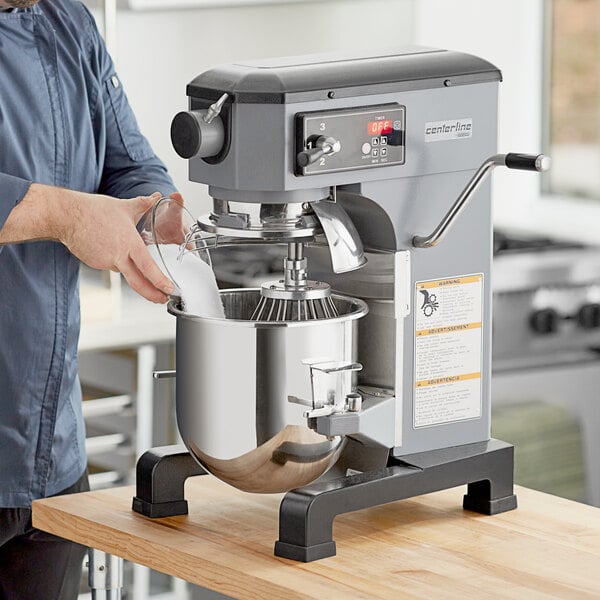 A man pouring liquid into a Centerline commercial mixer.