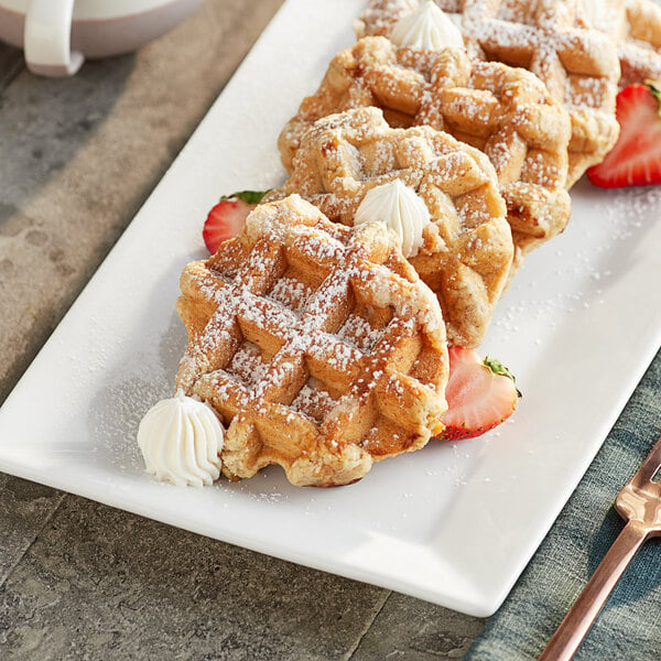 A plate of Vafels vegan Liege waffles with strawberries and whipped cream on a table.