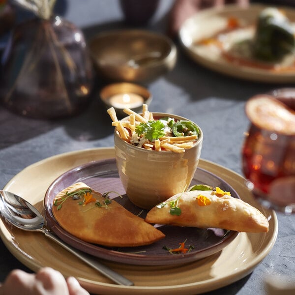 A close-up of a Libbey mauve terracotta stack plate with food on a table.