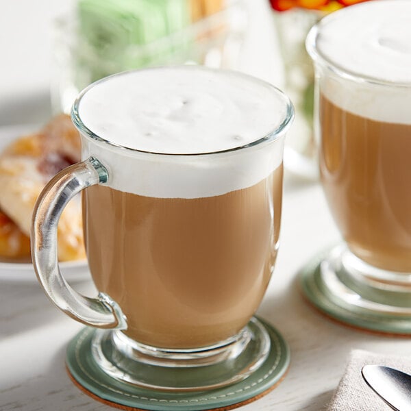 A glass mug of brown liquid with white foam made with Planet Oat Barista Edition Oat Milk.